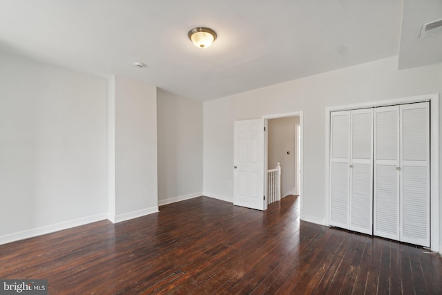 unfurnished bedroom with dark wood-type flooring and a closet