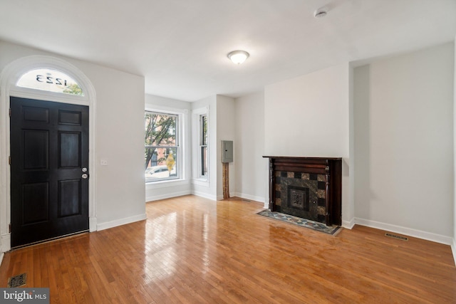 foyer entrance featuring a tiled fireplace, hardwood / wood-style flooring, and plenty of natural light