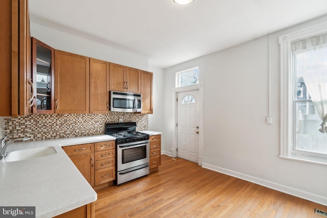 kitchen featuring light wood-type flooring, appliances with stainless steel finishes, sink, and decorative backsplash