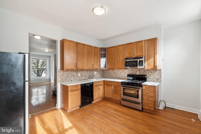 kitchen with light hardwood / wood-style floors, decorative backsplash, and appliances with stainless steel finishes