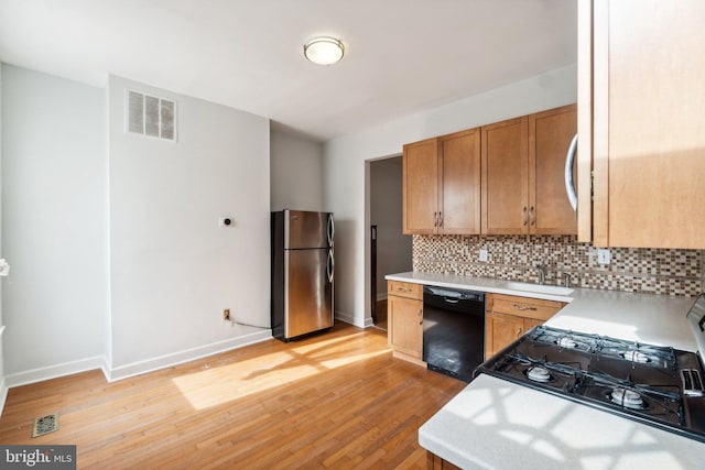 kitchen featuring black appliances, tasteful backsplash, and light hardwood / wood-style flooring