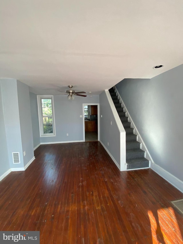 unfurnished living room with dark hardwood / wood-style flooring and ceiling fan