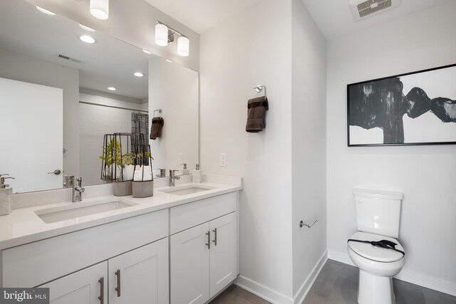 bathroom with double vanity, toilet, and tile patterned flooring