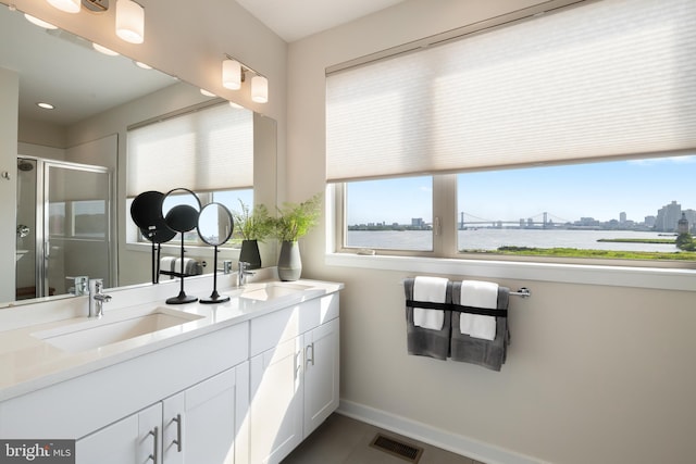 bathroom with a shower with door, a water view, tile patterned floors, and dual vanity