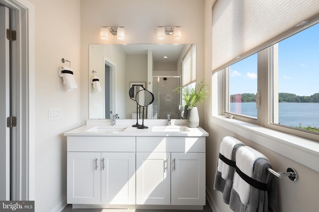 bathroom with dual bowl vanity, a water view, and an enclosed shower