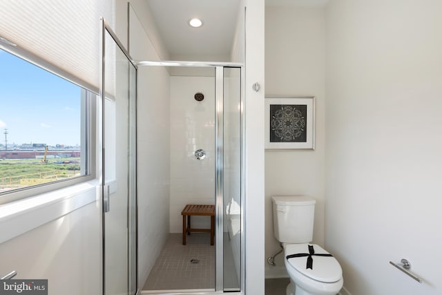 bathroom with a shower with shower door and toilet