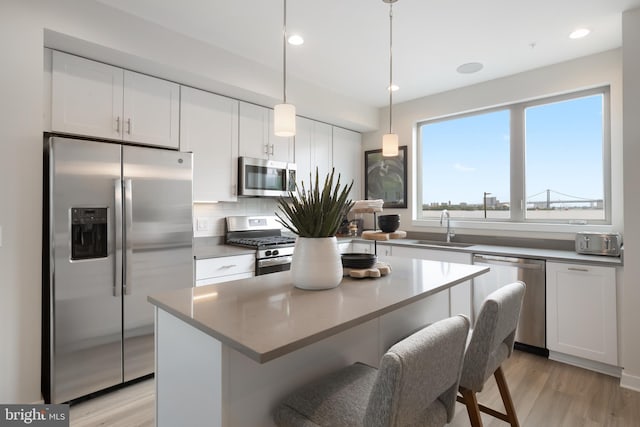 kitchen featuring white cabinets, a center island, light wood-type flooring, stainless steel appliances, and sink