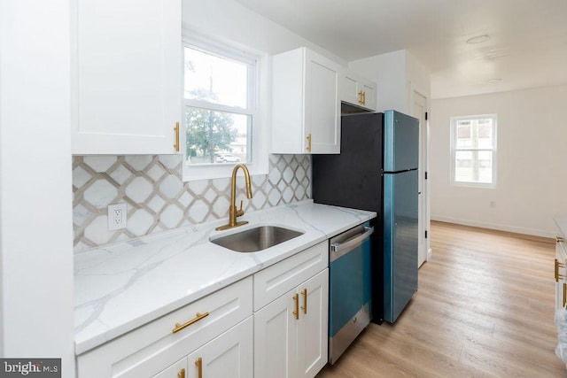 kitchen with sink, white cabinets, light stone counters, light hardwood / wood-style floors, and stainless steel appliances