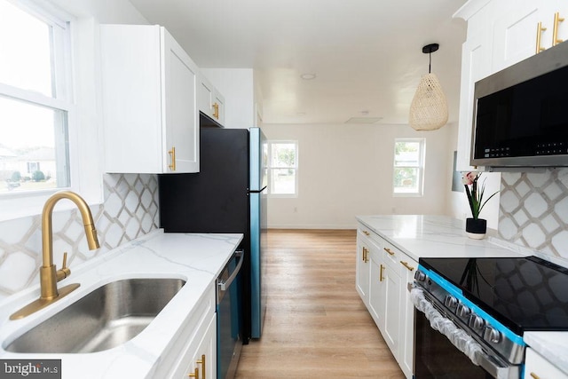 kitchen with white cabinetry, appliances with stainless steel finishes, sink, and decorative light fixtures