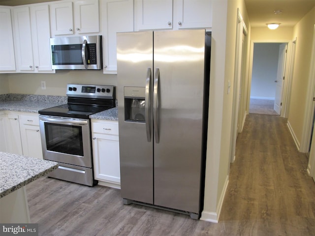 kitchen featuring appliances with stainless steel finishes, wood-type flooring, and light stone countertops