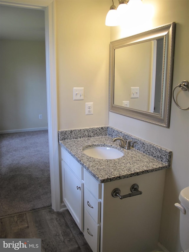 bathroom with wood-type flooring, vanity, and toilet