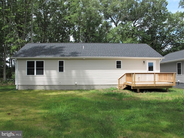 rear view of house with a wooden deck and a lawn