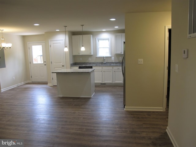 kitchen with dark hardwood / wood-style flooring, a kitchen island, hanging light fixtures, and white cabinetry