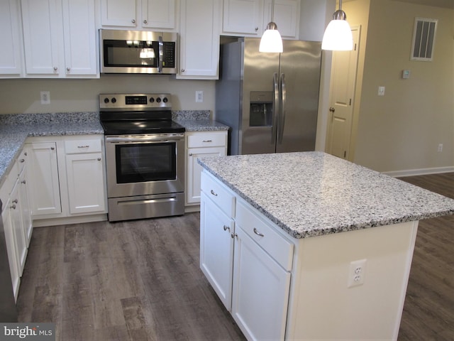 kitchen with dark wood-type flooring, a center island, appliances with stainless steel finishes, white cabinets, and light stone counters