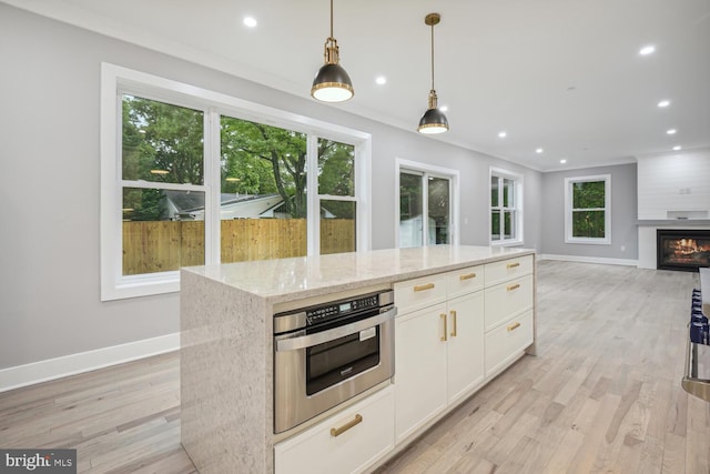 kitchen with oven, light stone countertops, white cabinetry, light hardwood / wood-style floors, and a fireplace