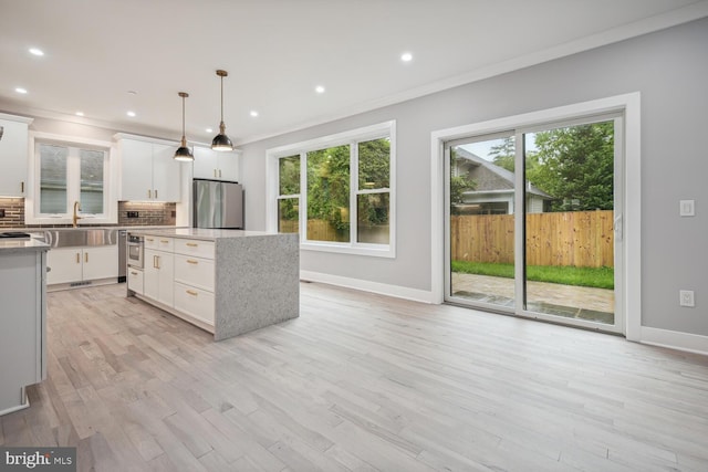 kitchen with tasteful backsplash, white cabinets, light wood-type flooring, and stainless steel refrigerator