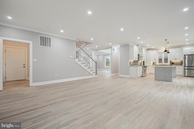 unfurnished living room featuring light hardwood / wood-style flooring and ornamental molding