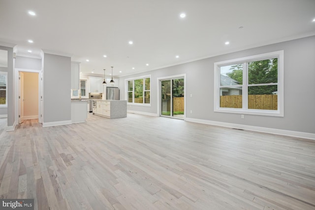 unfurnished living room with a healthy amount of sunlight, crown molding, and light hardwood / wood-style floors