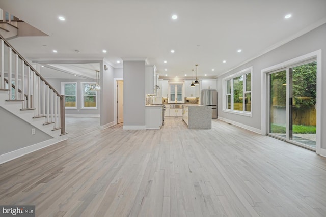 unfurnished living room featuring crown molding, plenty of natural light, and light hardwood / wood-style floors