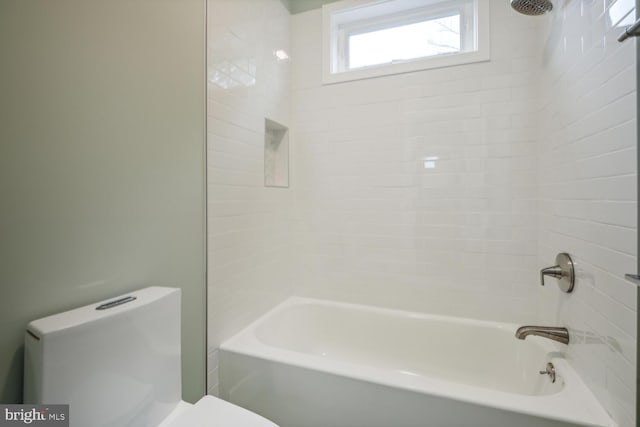 bathroom with toilet and tiled shower / bath