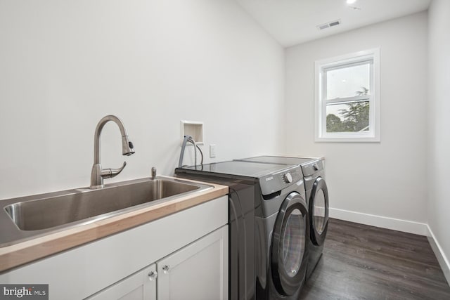 laundry area with sink, dark hardwood / wood-style floors, cabinets, and independent washer and dryer