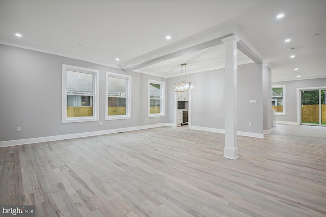 unfurnished living room featuring a notable chandelier, ornate columns, beamed ceiling, and light hardwood / wood-style floors