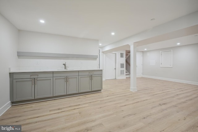 basement featuring sink and light hardwood / wood-style flooring