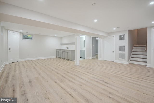 basement featuring light hardwood / wood-style flooring and sink