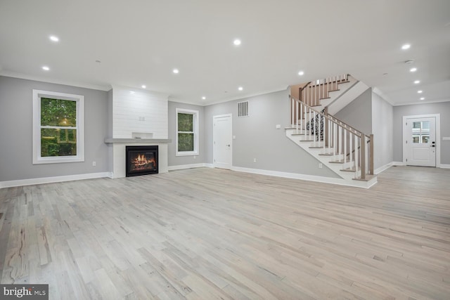 unfurnished living room featuring light hardwood / wood-style flooring, a fireplace, and crown molding