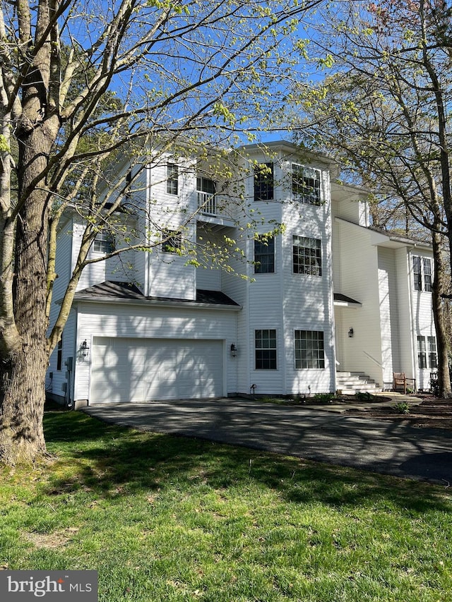 exterior space featuring aphalt driveway, a lawn, and an attached garage