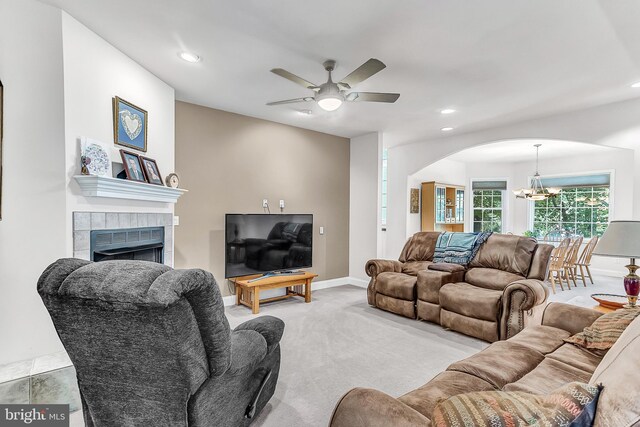 living room featuring ceiling fan with notable chandelier, light colored carpet, and a fireplace