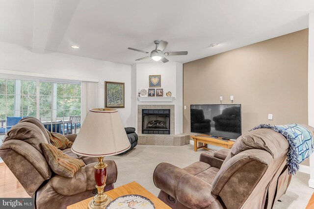 living room featuring ceiling fan, a fireplace, and beam ceiling