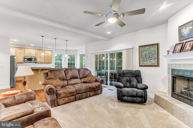 living room with a tiled fireplace, light hardwood / wood-style flooring, and ceiling fan