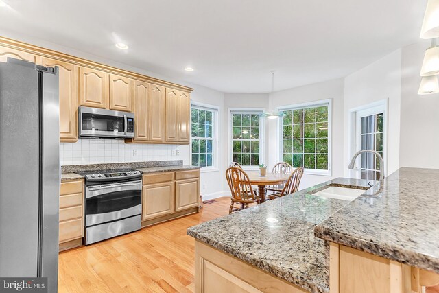 kitchen with hanging light fixtures, light hardwood / wood-style flooring, appliances with stainless steel finishes, and light brown cabinets