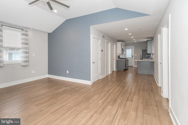 unfurnished living room featuring ceiling fan, light wood-type flooring, and vaulted ceiling