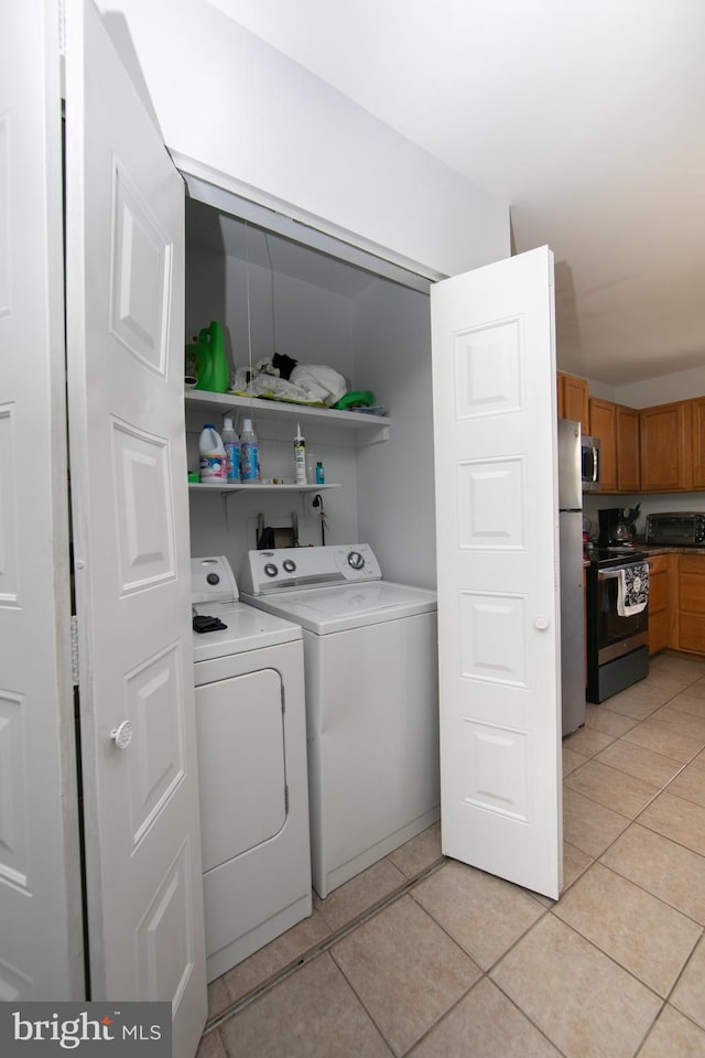 clothes washing area with washer and clothes dryer and light tile patterned floors