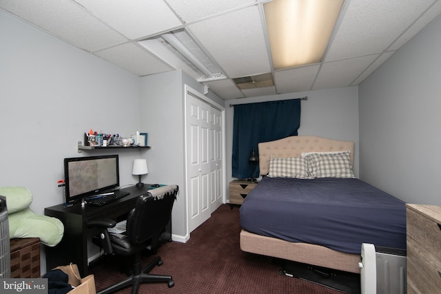 carpeted bedroom featuring a closet and a paneled ceiling