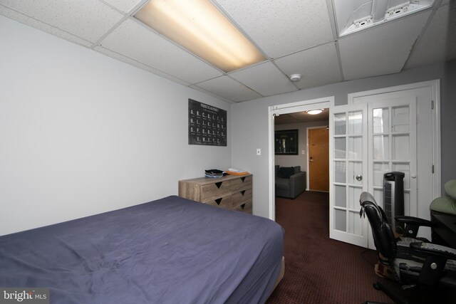 carpeted bedroom with french doors and a drop ceiling