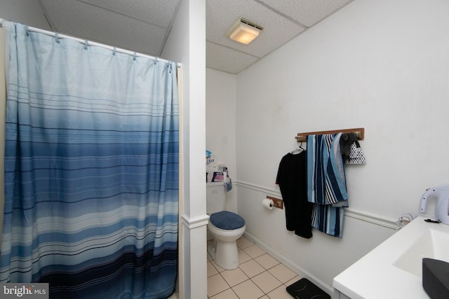 bathroom with a paneled ceiling, tile patterned flooring, toilet, and vanity