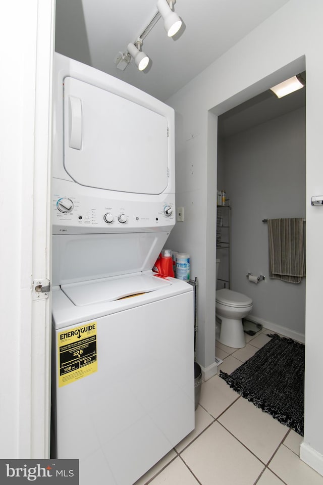 laundry area with light tile patterned floors and stacked washer / drying machine