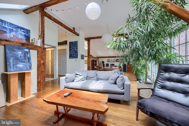 living room with beam ceiling, a skylight, high vaulted ceiling, and hardwood / wood-style floors