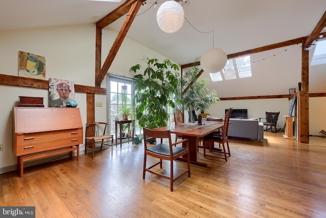 dining area with a skylight, high vaulted ceiling, and light hardwood / wood-style floors