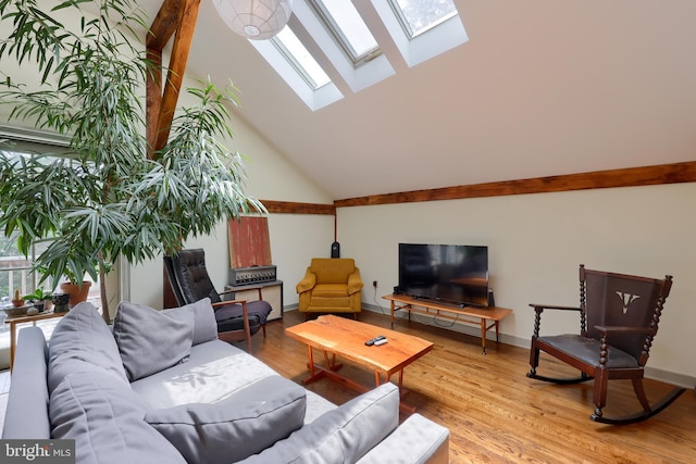 living room featuring wood-type flooring, a skylight, and high vaulted ceiling