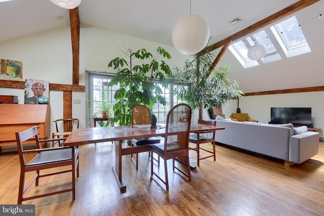 dining room with a skylight, hardwood / wood-style floors, and high vaulted ceiling