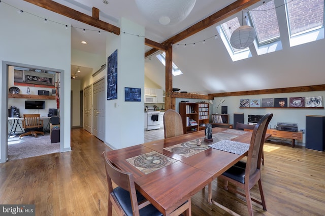 carpeted dining area with beamed ceiling, a skylight, and high vaulted ceiling