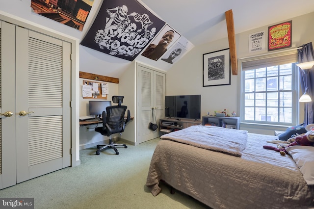 bedroom featuring multiple closets, vaulted ceiling, and carpet floors