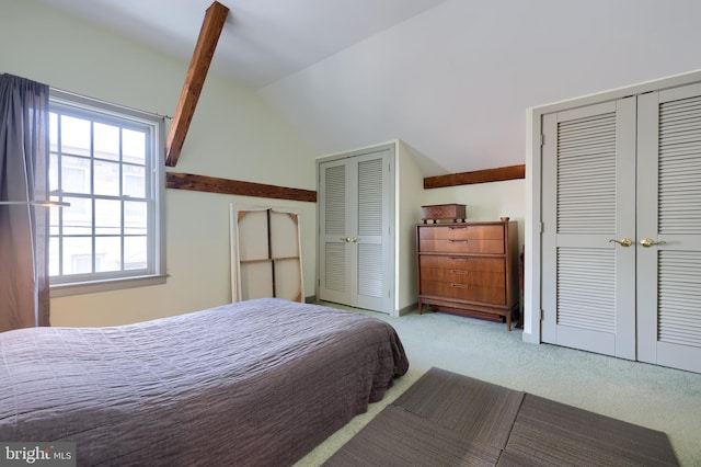 carpeted bedroom featuring two closets and lofted ceiling