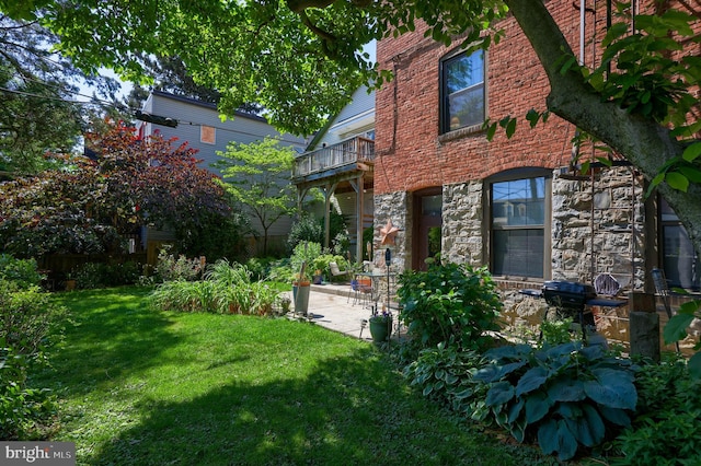 view of side of property with a patio area, a balcony, and a lawn