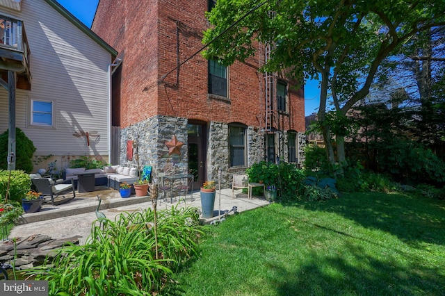 back of property featuring a patio, a yard, and an outdoor living space