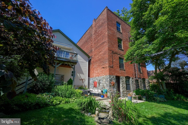 back of property featuring a balcony and a yard